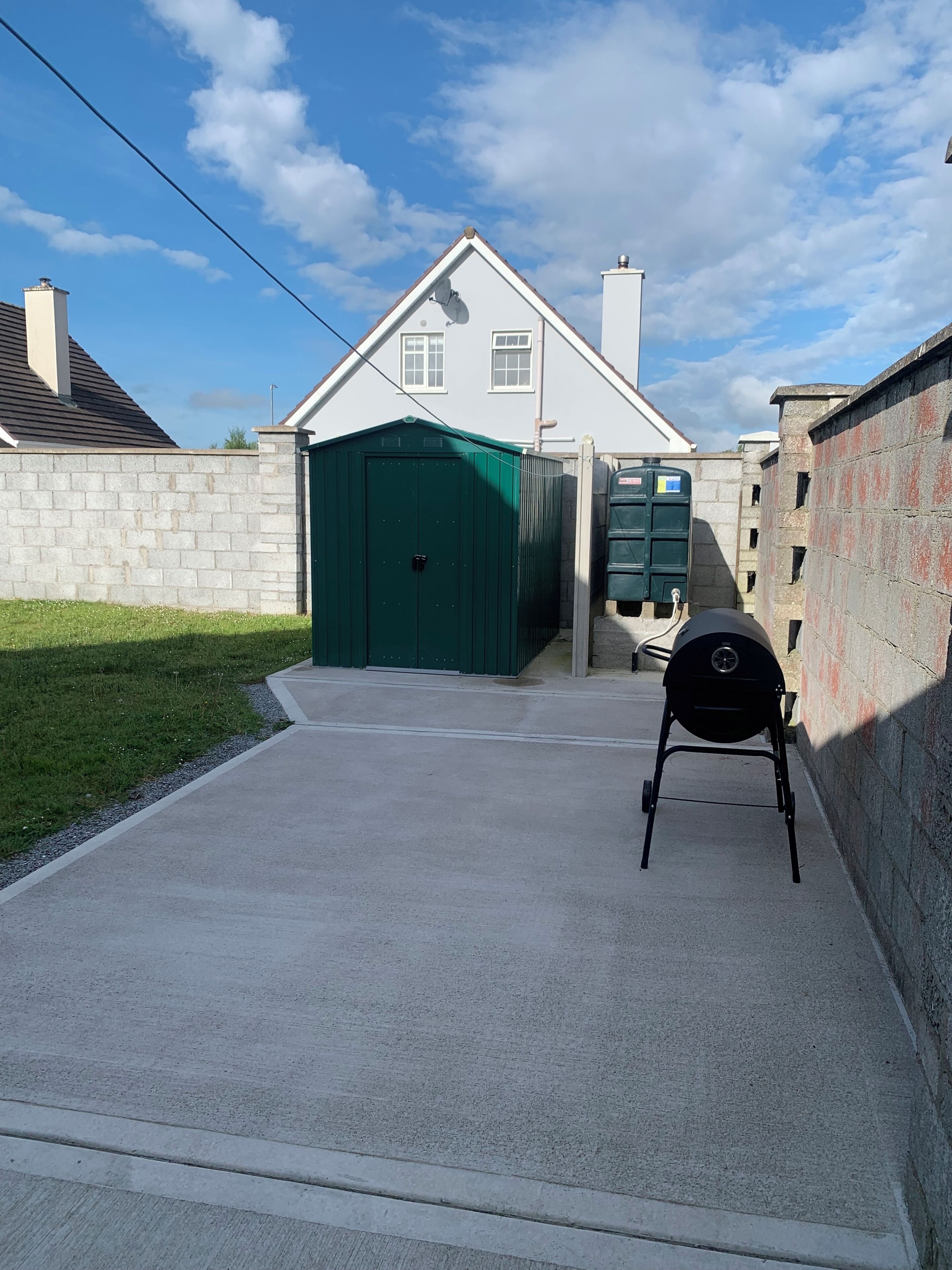 Un garaje con una puerta verde, una parrilla de barbacoa y un vehículo utilitario verde.