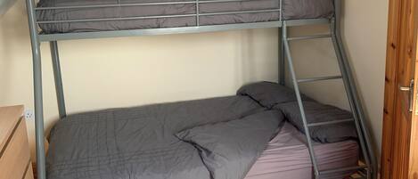A bunk bed with grey bedding in a room with wooden flooring and a sloped ceiling.