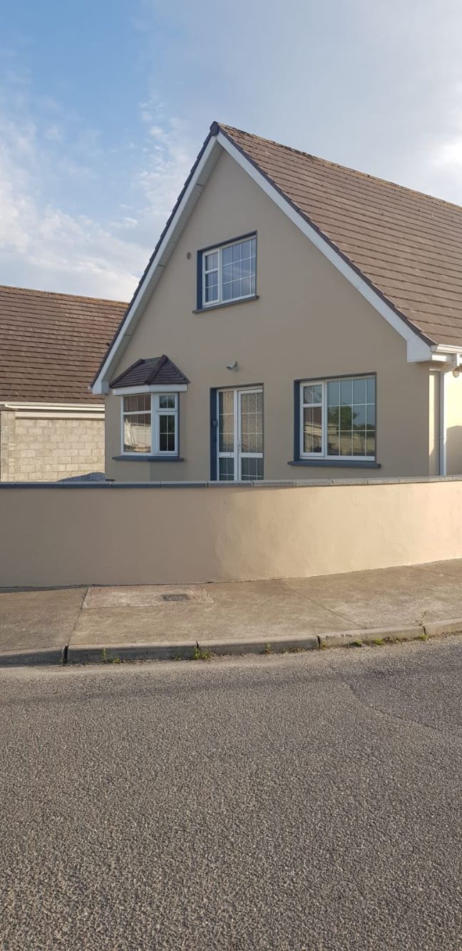Une maison à deux étages avec un toit en pente, un garage et une allée pavée.