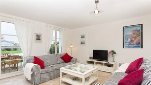 A living room with striped sofas, a coffee table, a TV, and a poster on the wall.