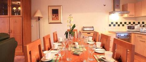 A dining area with a wooden table set for a meal, flanked by wooden chairs.