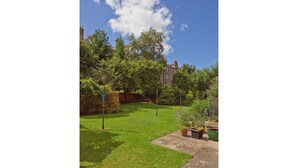 A well-maintained garden with a lawn, potted plants, and a brick wall. - Main Door Apartment in an enviable location (Edinburgh)