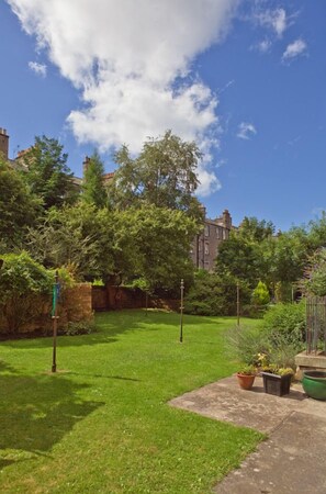 Un jardin bien entretenu, avec une pelouse, des plantes en pot et un mur en briques.