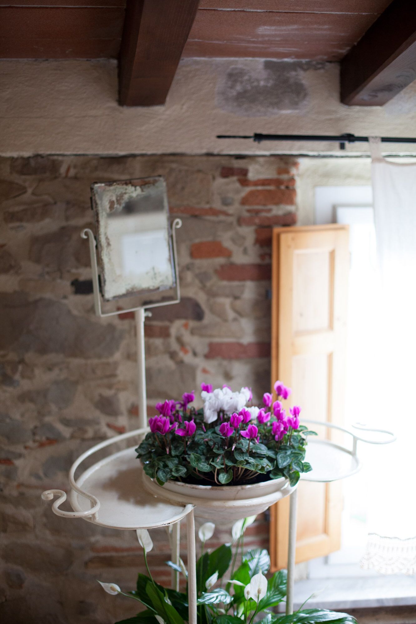 A rustic interior with a stone wall, a wooden door, and a white metal table with a potted plant.