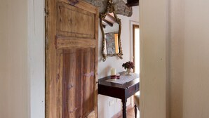 Een landelijke hal met een houten deur, een stenen muur en een betegelde vloer.