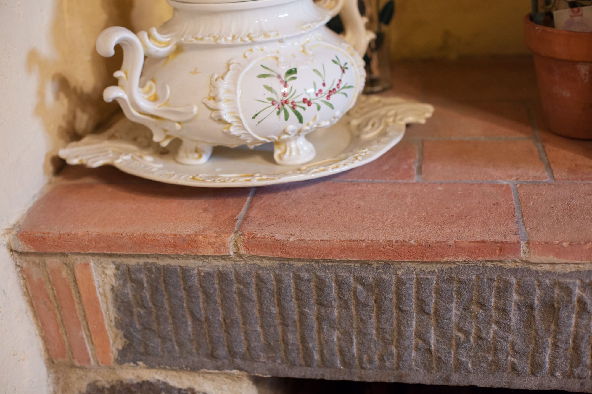 Una tureen de cerámica blanca con diseños florales sobre una superficie de azulejos.