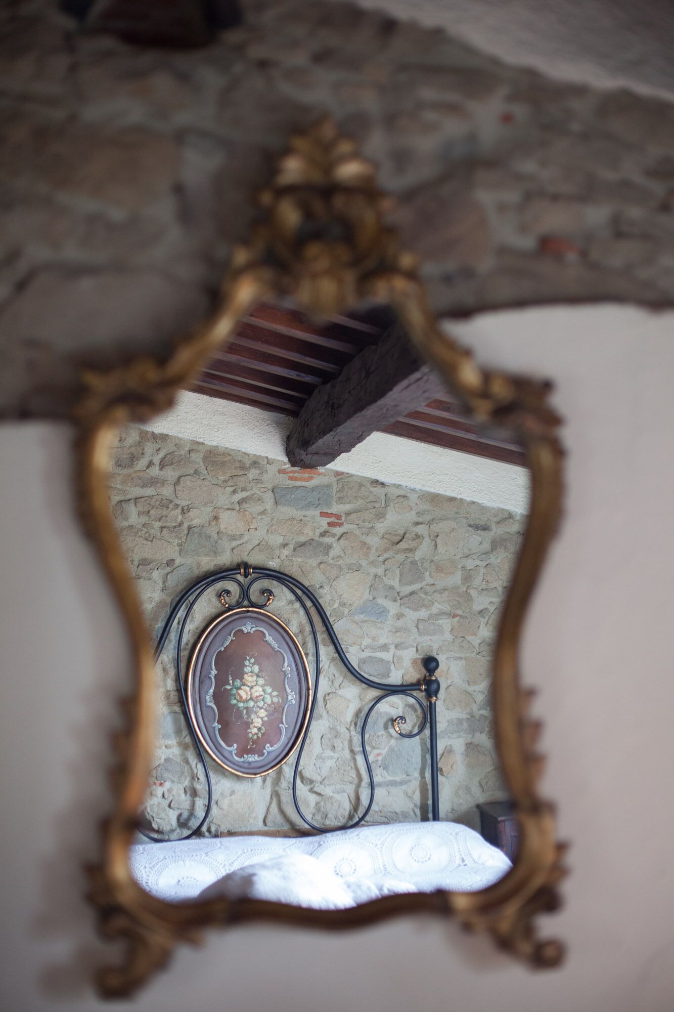 A mirror with an ornate frame, mounted on a wall with a stone texture.