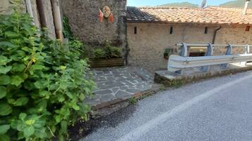 Une rue étroite bordée d’immeubles en pierre, avec une chaussée pavée et de la verdure.