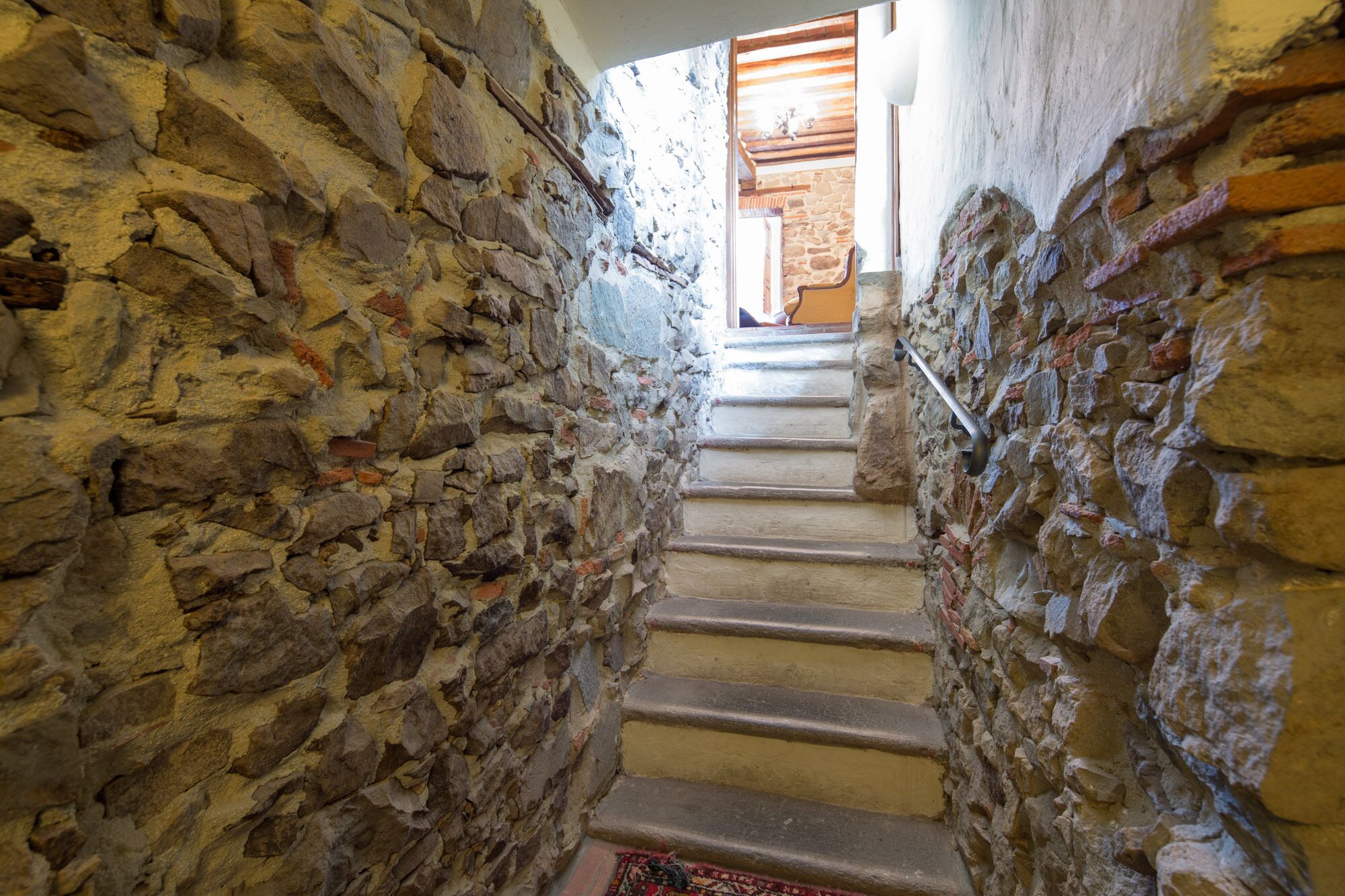 A narrow stone staircase leading to a wooden door.