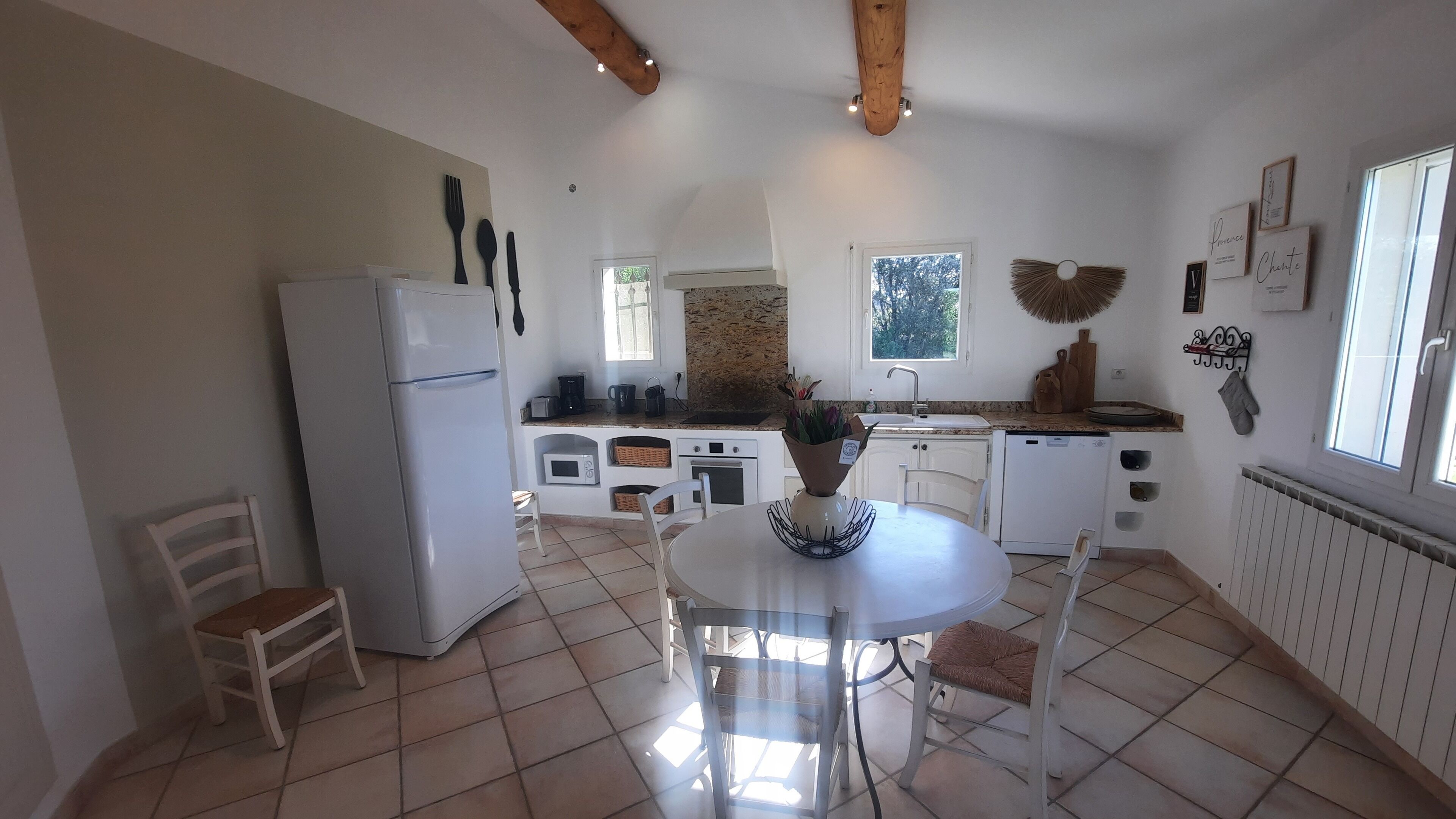 A kitchen with a dining table, chairs, a refrigerator, and a window.