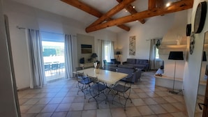 A spacious living area with a dining table, sofas, and a balcony with curtains. - In PROVENCE, Facing LUBERON, A LITTLE CORNER OF PARADISE, PRIVATE VILLA FOR 6 Pers (Cabrières-D'avignon)