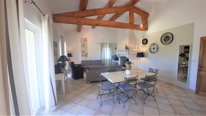 A spacious living area with a high ceiling, a sofa set, a dining table with chairs, and a television. - In PROVENCE, Facing LUBERON, A LITTLE CORNER OF PARADISE, PRIVATE VILLA FOR 6 Pers (Cabrières-D'avignon)
