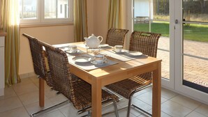 A dining area with a table set for four, surrounded by wicker chairs, a white teapot, and matching cups and saucers. - apartes holiday house with fireplace and sauna invites you to a relaxing holiday (Zirchow)
