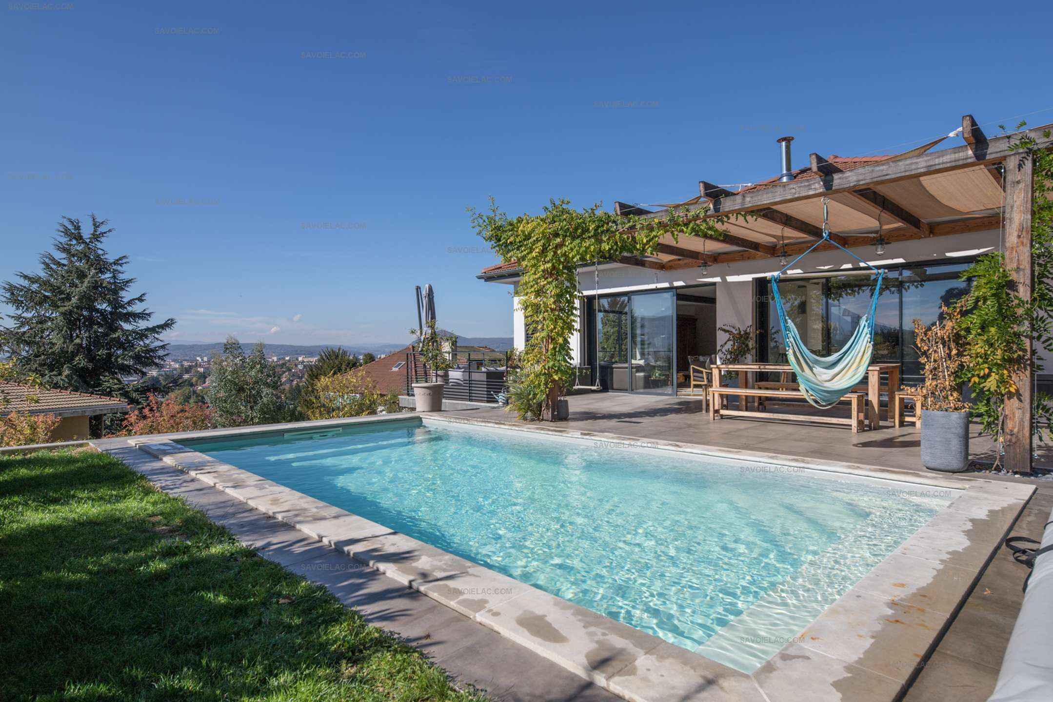 A swimming pool with a wooden deck and a hammock.