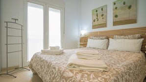 A bedroom with a bed, a towel rack, and two paintings on the wall. - Near La Caleta. Ascenseur.WIFI (Cádiz)