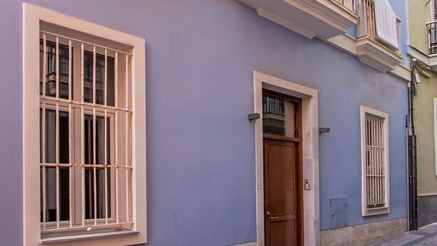 A two-story building with a balcony, a wooden door, and a window with bars. - Near La Caleta. Ascenseur.WIFI (Cádiz)