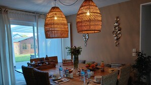 Un coin repas avec une table en bois, des chaises en osier et un luminaire suspendu.