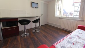 Una cocina moderna con microondas, dos taburetes de bar y un televisor montado en la pared.