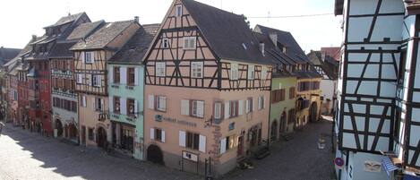 A traditional European street with half-timbered buildings, cobblestone pavement, and a clear sky.