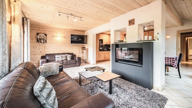 A cozy living room with a leather sofa, a flat-screen TV, and a fireplace. - Beautiful 4-star duplex apartment available for rent in the Centre des Gets (Les Gets)