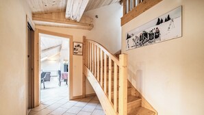 A wooden staircase with a handrail leading to an upper floor. A sign on the wall depicts a ski scene. - Beautiful 4-star duplex apartment available for rent in the Centre des Gets (Les Gets)