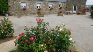 A stone building with a tiled roof, multiple windows, and flower boxes. - Unique all comfort Longere, close to the sea of Iroise (Ploumoguer)