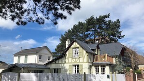 Ett tvåvåningshus med ett vitt staket, en balkong och en skorsten.