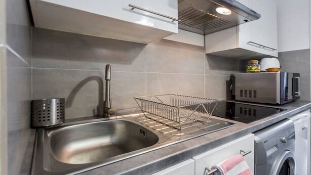 A modern kitchen with a stainless steel sink, a dish rack, a microwave, and a built-in oven. - Bordeaux Hyper Center ville Rue Courbin renovated, cozy and bright (Bordeaux)