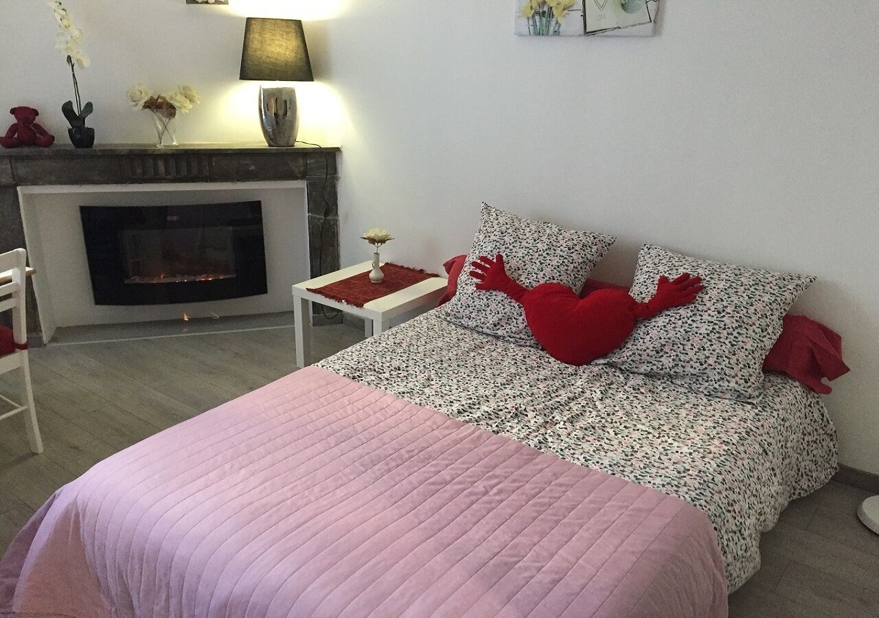 Une chambre à coucher avec un lit, une cheminée, une table de chevet et une chaise.