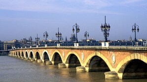 A stone bridge with multiple arches over a body of water, featuring street lamps and a railing. - Bordeaux Hyper Center ville Rue Courbin renovated, cozy and bright (Bordeaux)