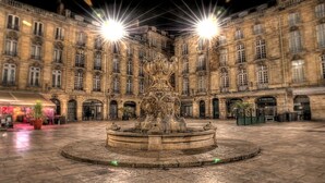 A courtyard with a central fountain, surrounded by historic stone buildings with multiple windows and arched doorways. - Bordeaux Hyper Center ville Rue Courbin renovated, cozy and bright (Bordeaux)