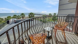 A balcony with a curved railing, two wicker chairs, a small table, and a view of the beach and ocean. - Romantic Oceanfront View, Discounted, Pools (Myrtle Beach)