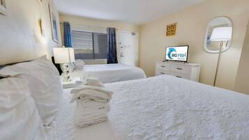A hotel room with two beds, a TV, a desk, and a bathroom.