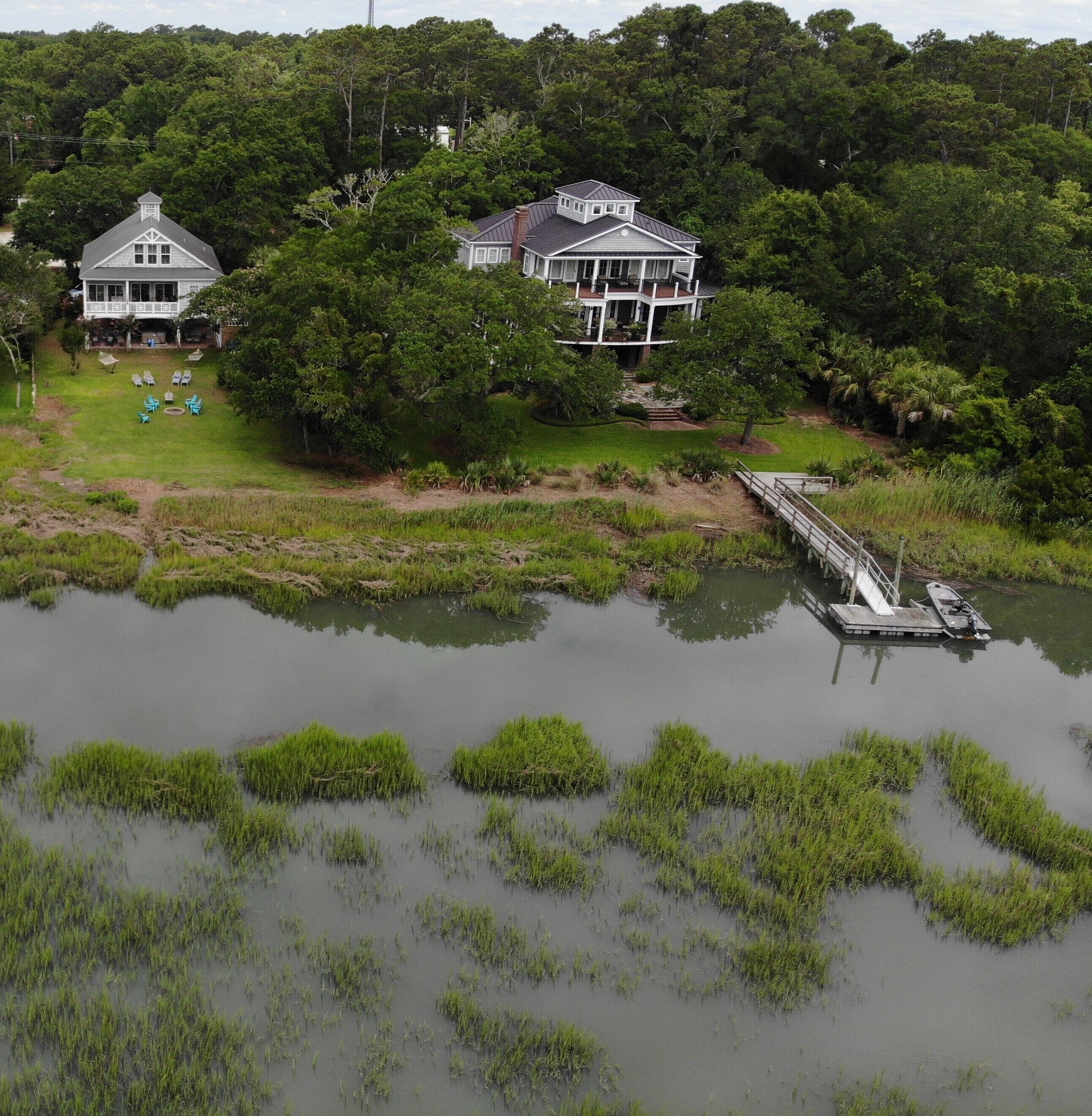 Une grande maison avec un quai s’avançant dans un lac, entourée d’une végétation luxuriante.