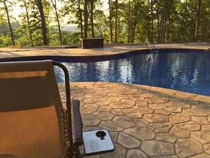 A pool area with a stone patio, a lounge chair, and a wooden bench. - Cabin on Dale Hollow Lake - Hike to lake (Monroe)