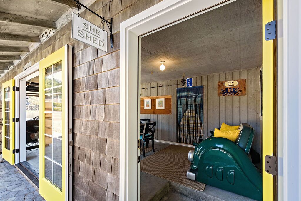 Un interno accogliente con un'auto d'epoca verde, una parete in legno e un cartello con la scritta 'She Shed'.