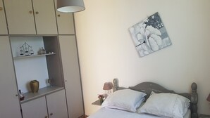 A bedroom with a bed, a nightstand, a lamp, a wall-mounted artwork, and a wardrobe. - Bottom of villa for rent, seasonal rental (Le GOSIER)