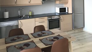 A modern kitchen with wooden cabinets, a stainless steel refrigerator, a microwave, and a dishwasher. - Downtown Apartment by Old Harbor (101 Reykjavík)