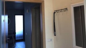 A hallway with a chandelier, a coat rack, and a door leading to another room. - Downtown Apartment by Old Harbor (101 Reykjavík)