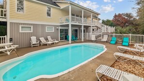 Una casa a due piani con una veranda coperta e una piscina.
