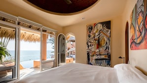 A bedroom with a large bed, a view of the sea, and a painting on the wall. - Luxurious Oceanfront Villa - Steps from Manzanillo Beach - Best View in Puerto (Puerto Escondido)