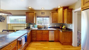 A kitchen with wooden cabinets, a stainless steel dishwasher, a granite countertop, and a window providing natural light. - TACIT SHADOW - "Escape" Two Bedroom Suite w/ Balcony - Sleeps 9 Guests in Beds (Parowan)