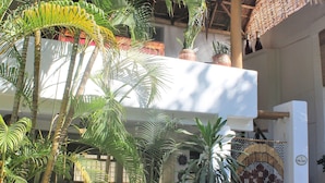 Un edificio con techo de paja, rodeado de plantas en macetas y una verja.
