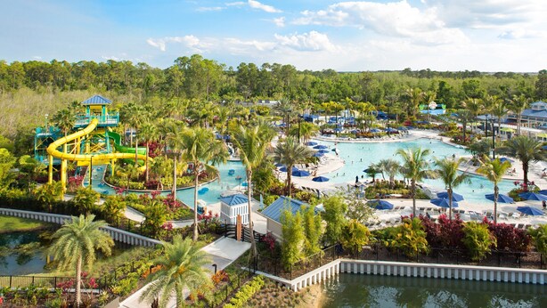 Un resort con varias piscinas, palmeras y un parque acuático.