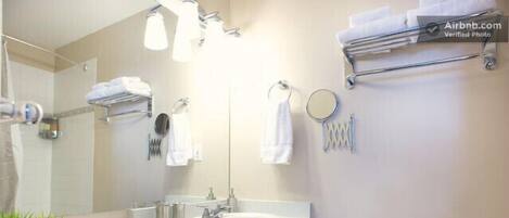 Un baño moderno con un lavamanos blanco, muebles oscuros, un espejo y un perchero para toallas.