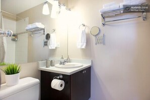 A modern bathroom with a white sink, dark cabinetry, a mirror, and a towel rack.