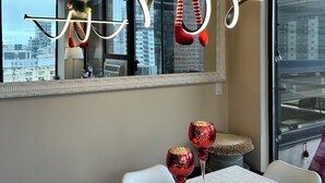 A dining area with a table set for two, a hanging ornament, and a view of the city through large windows.