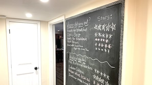 Um corredor com uma porta branca e uma lousa listando atrações e eventos locais.
