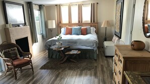 Quarto com cama, poltrona, cômoda e lareira.