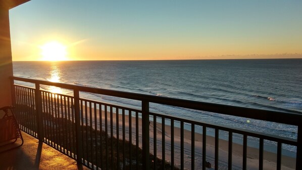 Un balcon avec vue sur l’océan au coucher du soleil.